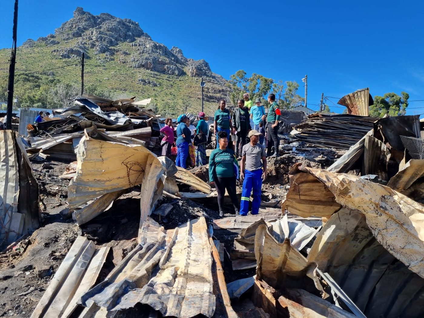 Archive photograph of residents and relief workers among fire-damaged homes in Imizamo Yethu, Hout Bay, in March 2023